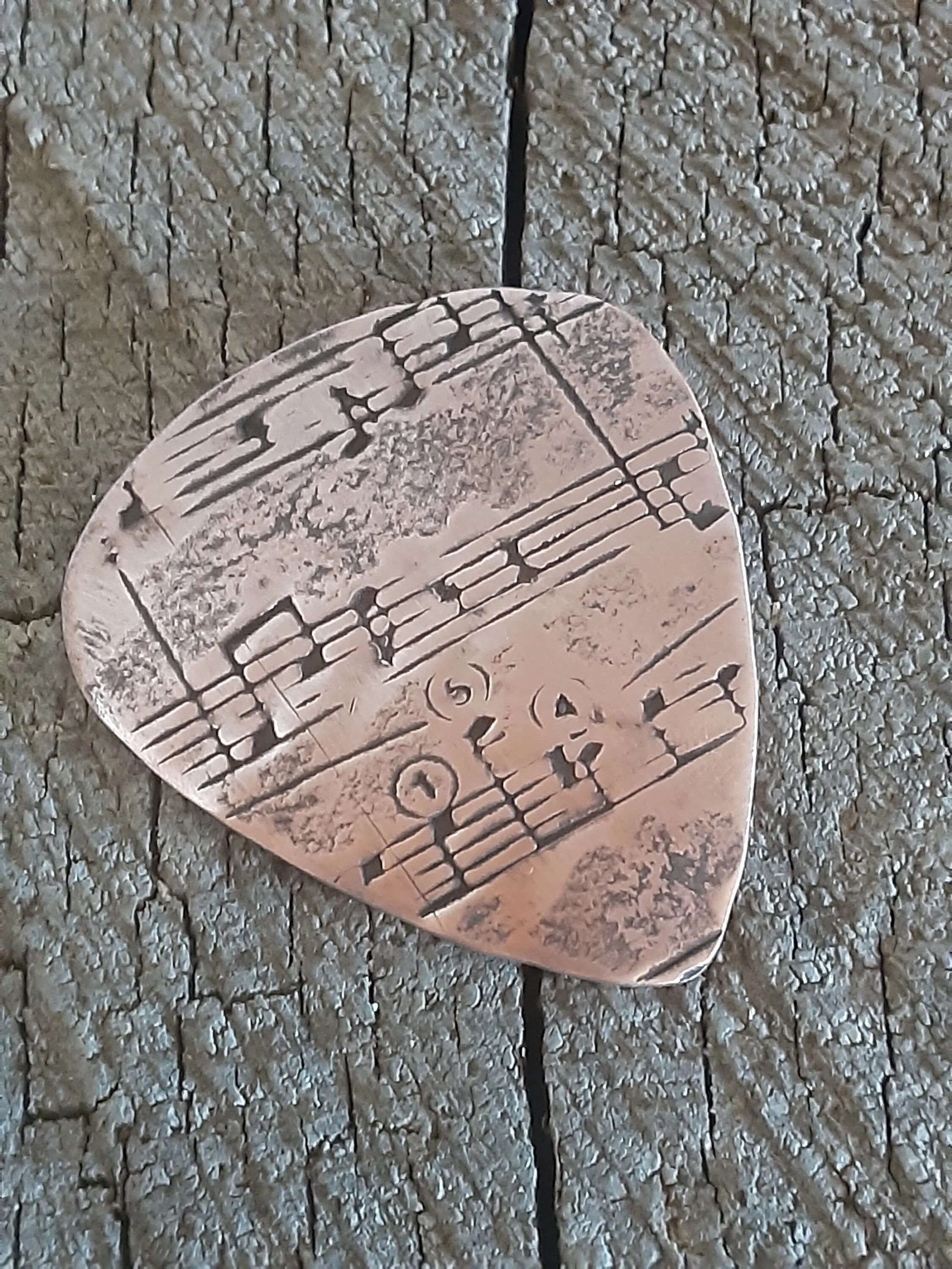 Copper guitar pick with music notes