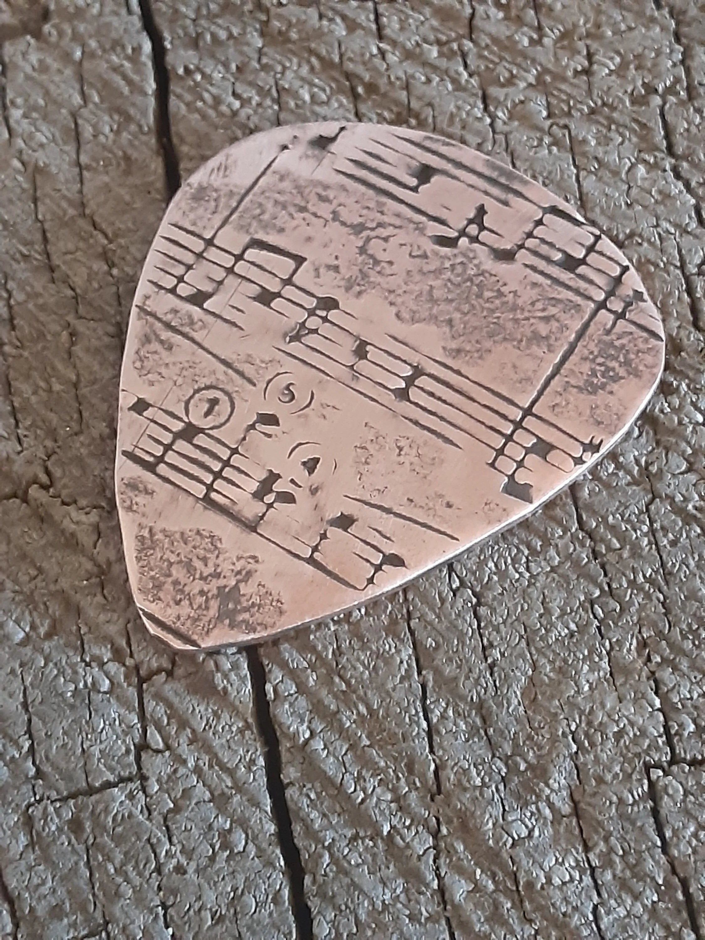 Copper guitar pick with music notes