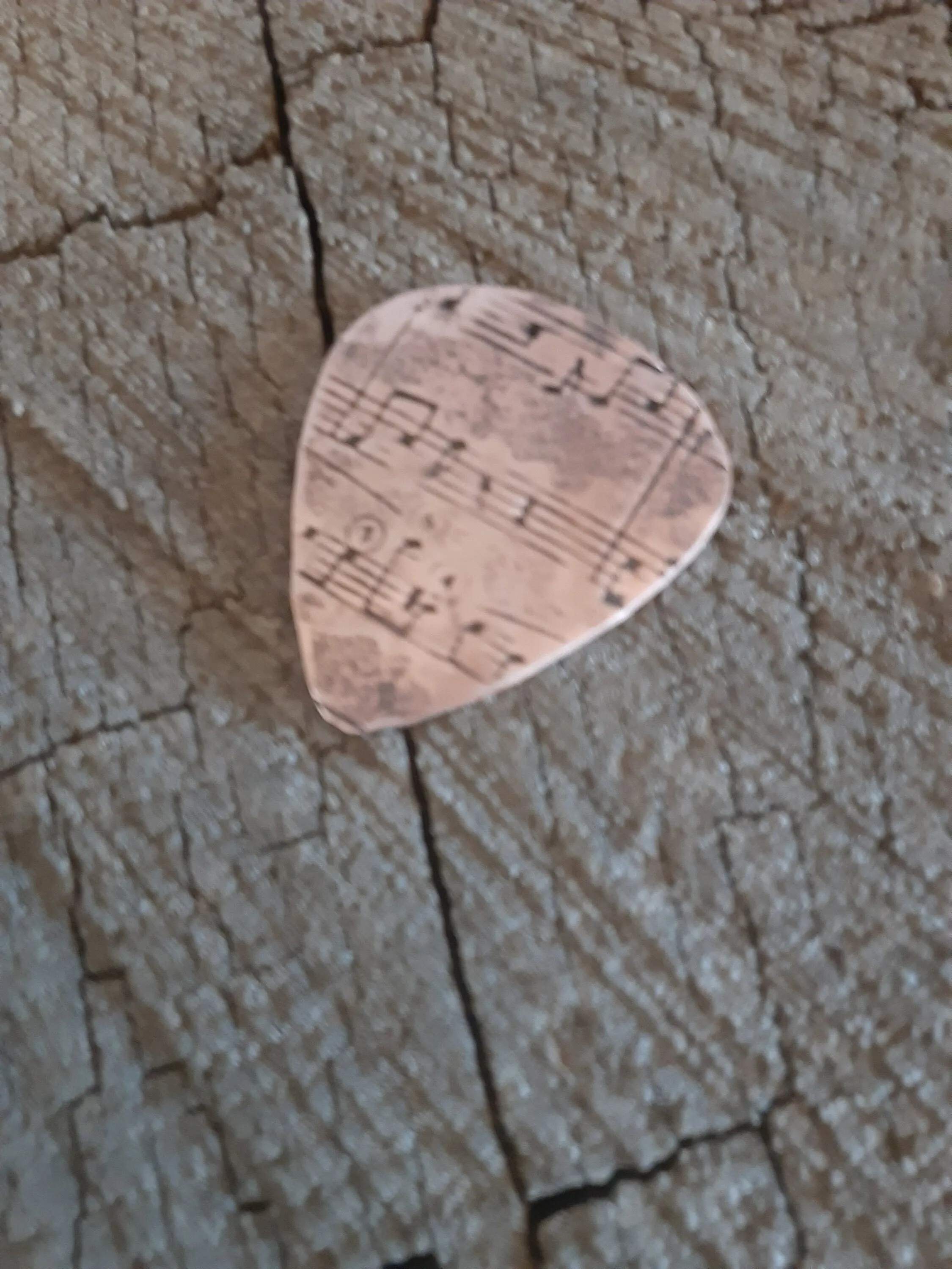 Copper guitar pick with music notes